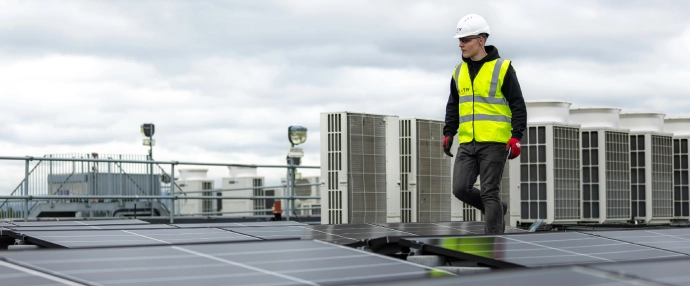 Ein Techniker von Solarom läuft auf einem Flachdach eines Firmengebäudes in Fellbach an montierten Solarmodulen vorbei.